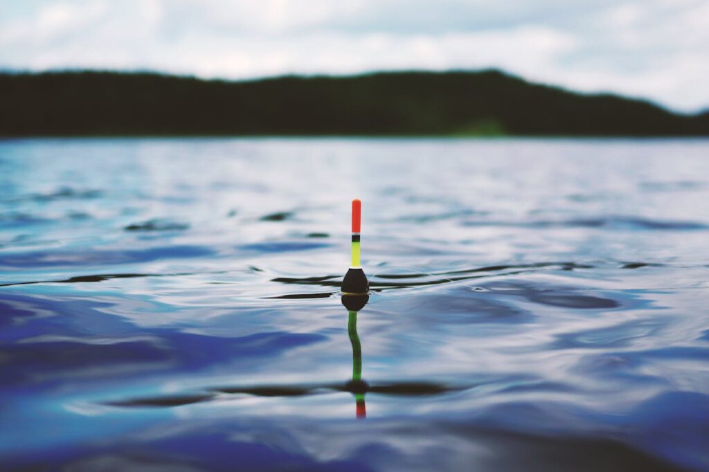 pexels-photo-190294 Vibrant fishing float gently resting on a serene blue water surface, ideal for travel and nature themes.