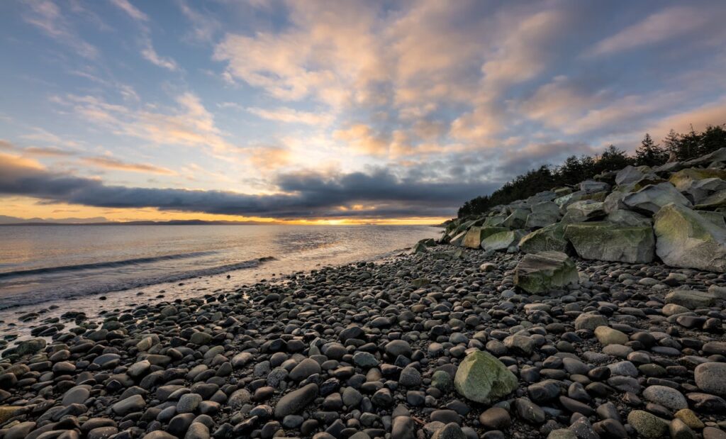 pexels-photo-3774243 Beautiful sunset over a rocky beach in Courtenay, BC, with dramatic clouds and calm sea.